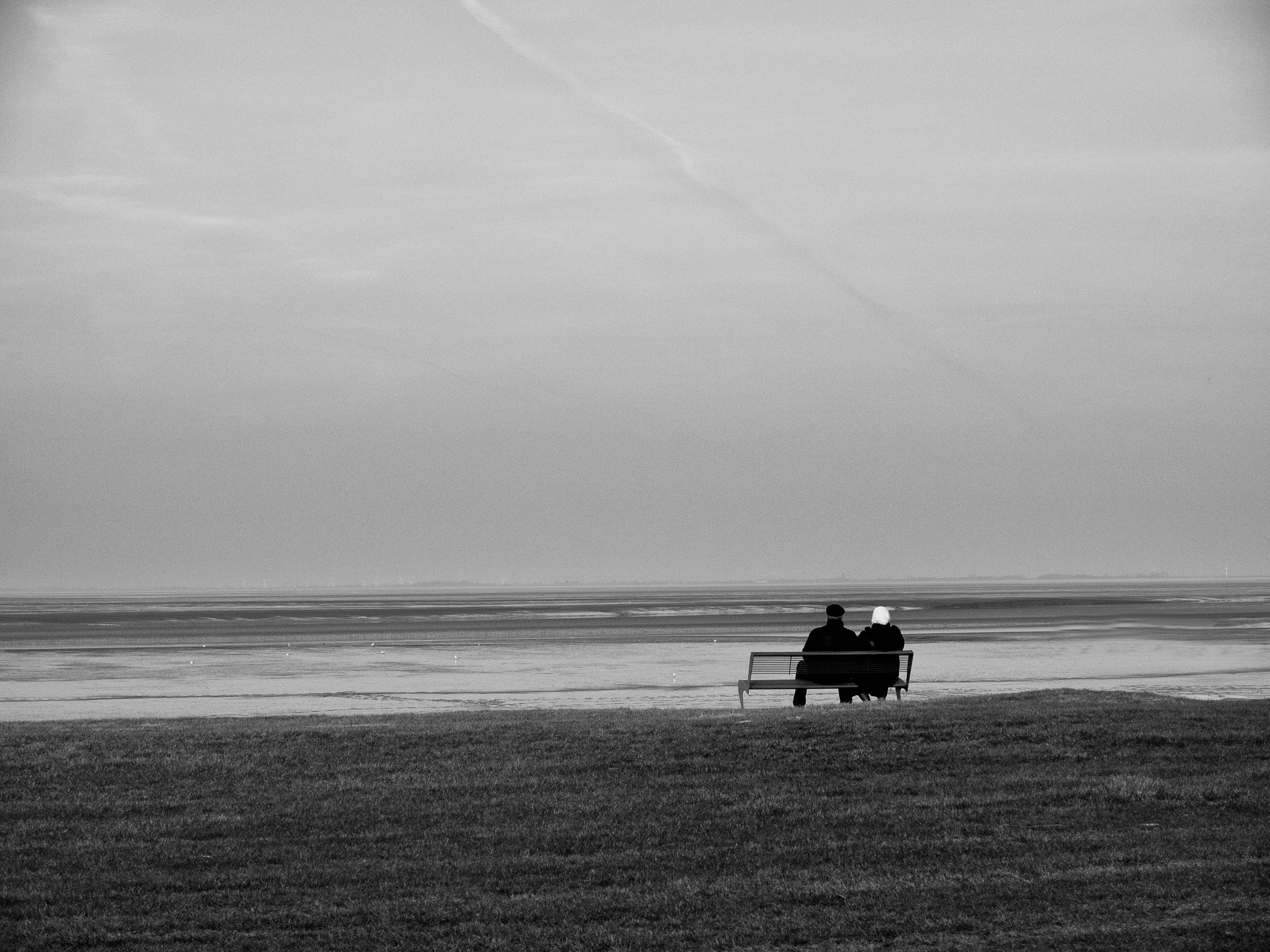 People sitting on a bench near a beach.